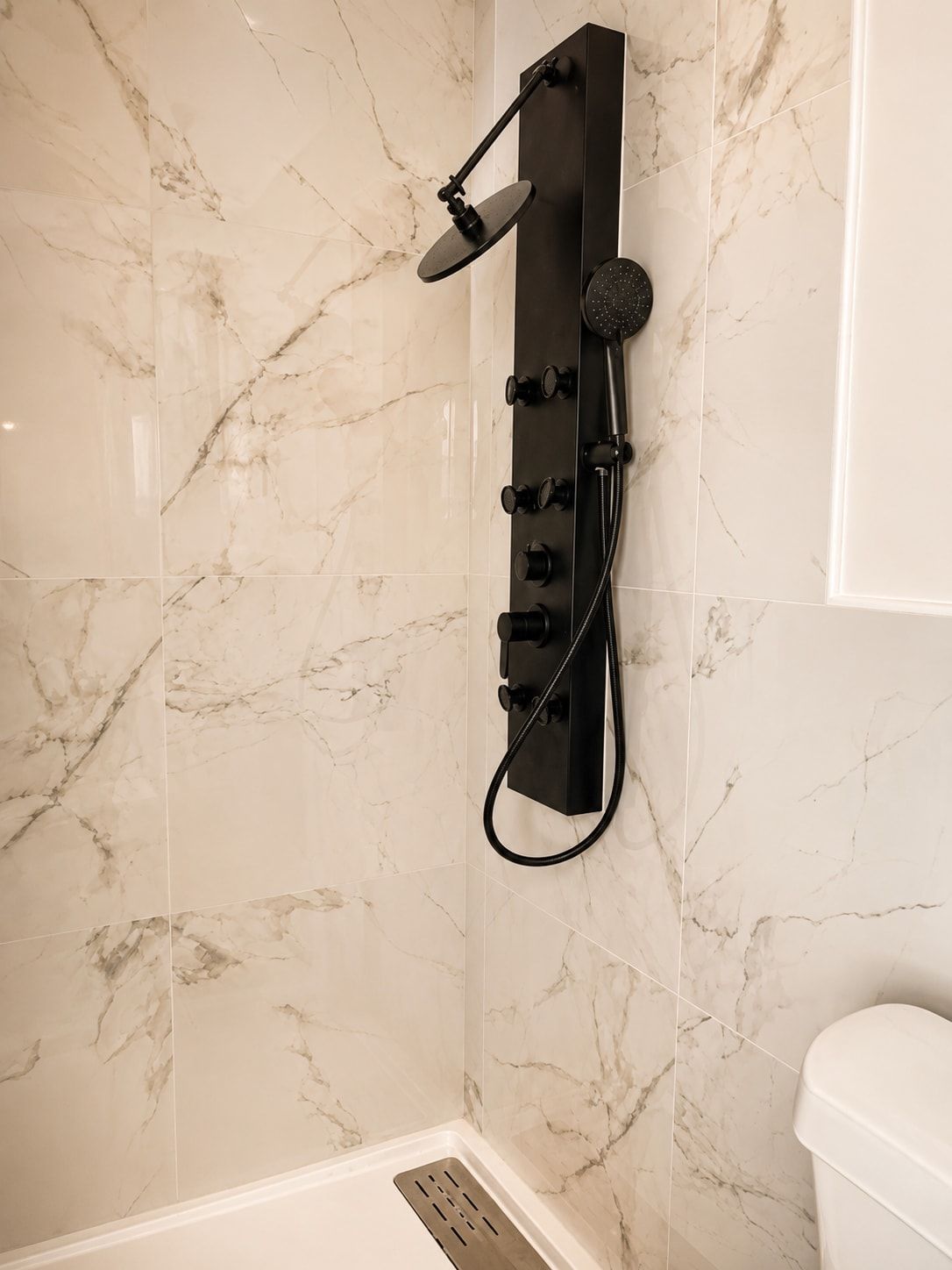 Une salle de bain moderne avec une colonne de douche verticale adossée à un mur en marbre.