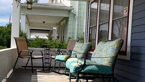 Une véranda abritée, aménagée avec du mobilier d’extérieur, notamment des chaises et une table.