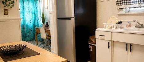 A kitchen with a stainless steel refrigerator, a sink with a faucet, and a trash bin.