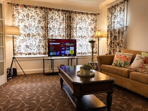 A living room with a flat-screen TV, a sofa, a coffee table, and patterned curtains. - Gorge View Vacation Home Niagara Falls 5Bed 11PPL (Niagara Falls)
