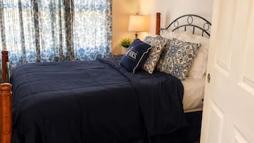 A bedroom with a bed, a nightstand, a lamp, and a door.