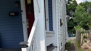 Une maison d'habitation avec une porte rouge, des balustrades blanches et le numéro « 2661 » inscrit sur le mur.