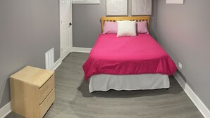 Une chambre à coucher avec un lit, une table de chevet en bois et une fenêtre.