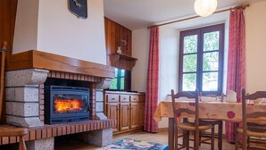 Una habitación acogedora con chimenea de piedra, muebles de madera y una ventana con cortinas.
