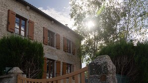 Un edificio de piedra con contraventanas y portón de madera.