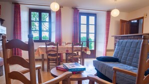 Un comedor acogedor con una mesa dispuesta para cuatro personas, sillas de madera y dos faroles de papel colgantes.