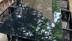 Una terraza con una mesa y sillas, rodeada por una barandilla de madera y un dosel superior.