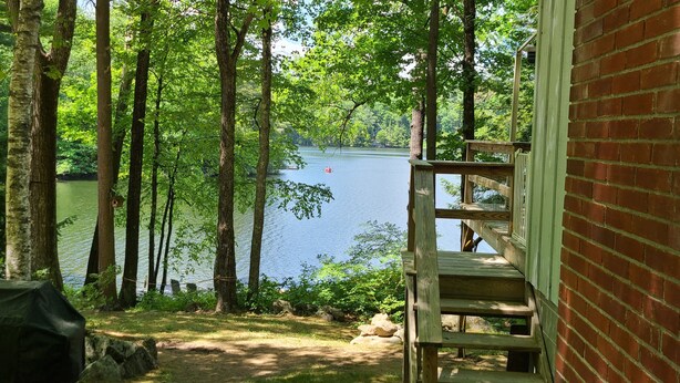 A wooden deck with a view of a lake surrounded by trees. -  Dog friendly lakefront home w/fireplace near Lk George. Telecommuters welcome! (Fort Ann)