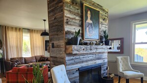 Un salon avec une cheminée, un canapé, un fauteuil et une plante en pot.