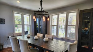 Une salle à manger avec une table en bois, six chaises rembourrées et un lustre.