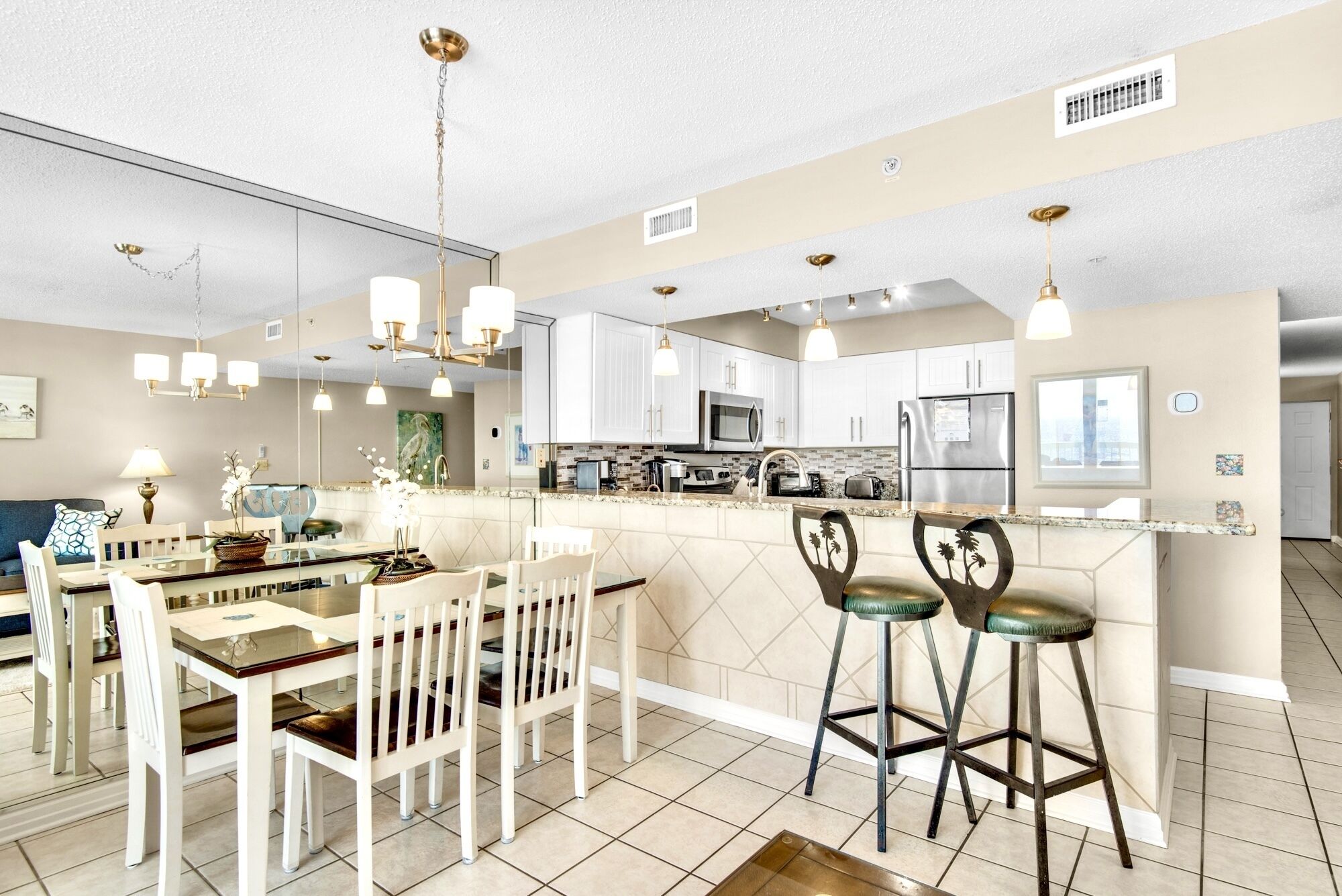 A modern kitchen with white cabinets, stainless steel appliances, and a central island with bar stools.
