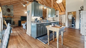 Une cuisine spacieuse avec des poutres en bois, une cheminée en pierre et des appareils électroménagers modernes.