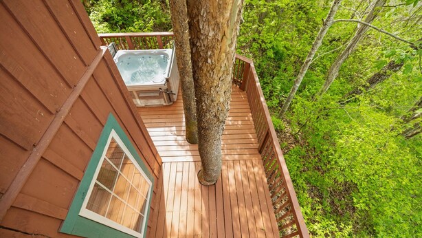 A wooden deck with a hot tub, surrounded by lush greenery. - Under 1 mile from Natural Bridge State Park! (Slade)