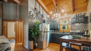 A kitchen with wooden cabinets, a stainless steel refrigerator, a microwave, and a wooden dining table with bar stools. - Under 1 mile from Natural Bridge State Park! (Slade)