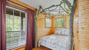 A wooden cabin bedroom with a bed, curtains, and a branch with lights. - Under 1 mile from Natural Bridge State Park! (Slade)