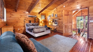 Una camera da letto accogliente in legno con un grande letto, una scrivania e vista sull'esterno.