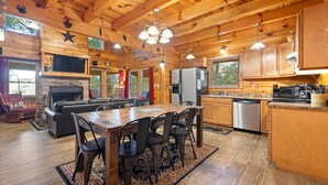 A log cabin interior with a dining area, kitchen, and living room. - Nestled in a scenic backdrop with captivating mountain valley view (Rogers)