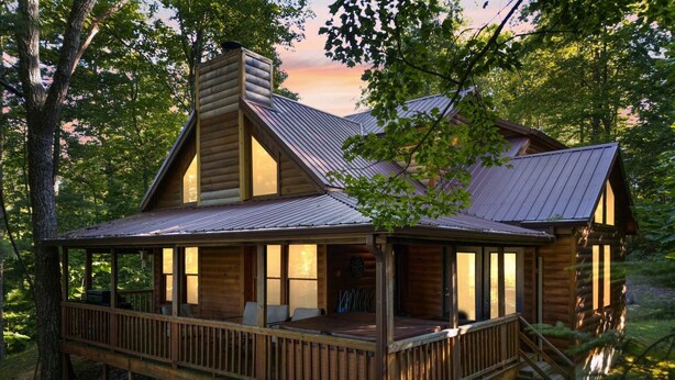 A log cabin with a porch, large windows, and a chimney. - Nestled in a scenic backdrop with captivating mountain valley view (Rogers)