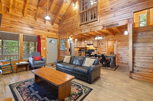 Interior acogedor de una cabaña con detalles de madera, un comedor y una sala de estar con sofá y mesa de centro.
