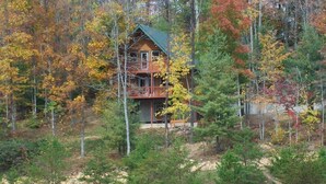 Een vakantiehuis omgeven door herfstbladeren, met een terras en een steiger.