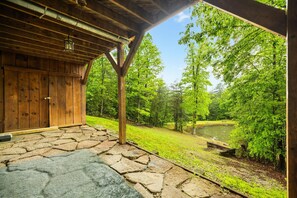 A wooden cabin with a stone patio leading to a covered porch.