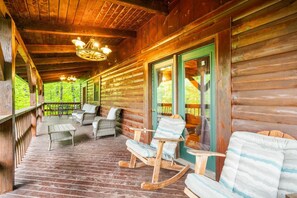 A wooden cabin with a porch, rocking chairs, and a covered seating area. - Large Log home, private pond with dock, pool table, hot tub & internet. (Rogers)
