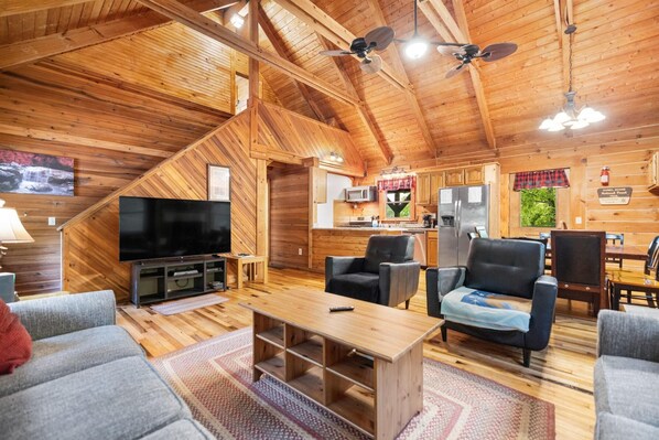 A wooden interior with a TV, seating, kitchen, and a sign indicating a trail.
