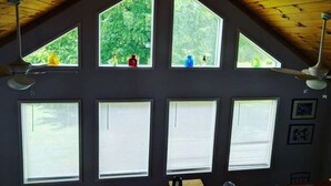 Ein Zimmer mit geneigter Decke, mehreren Fenstern und Deckenventilatoren.