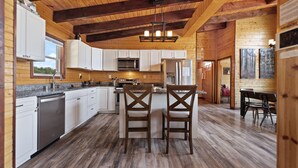 A modern kitchen with wooden beams, white cabinets, and a central island with two chairs. - Nearly 360 degree Mountain View! Private setting, Big Hot Tub, Wi-Fi, Gas Grill (Campton)