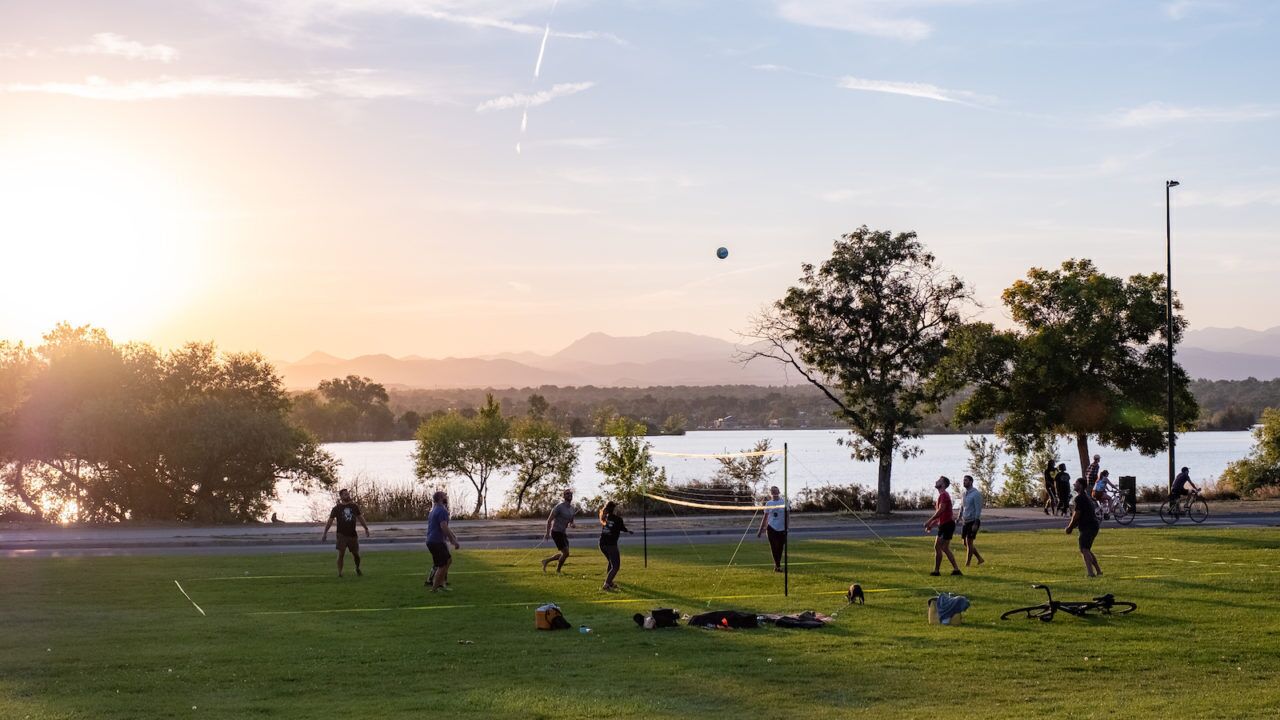 A park with a grassy field, trees, and a body of water in the background.