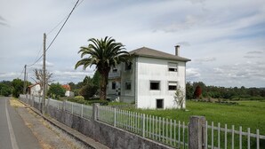 Un bâtiment à deux étages, à l’extérieur blanc et doté d’un toit en tuiles, entouré d’une clôture blanche et d’un palmier.