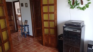 Une pièce avec un sol carrelé, des portes en bois, une table d’appoint bleue et un système audio noir.