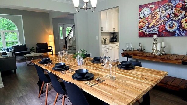 Un coin repas avec une table en bois dressée pour six personnes, entourée de chaises noires.