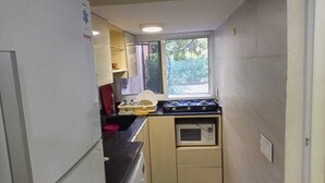Een kleine keuken met een koelkast, magnetron, fornuis en spoelbak.
