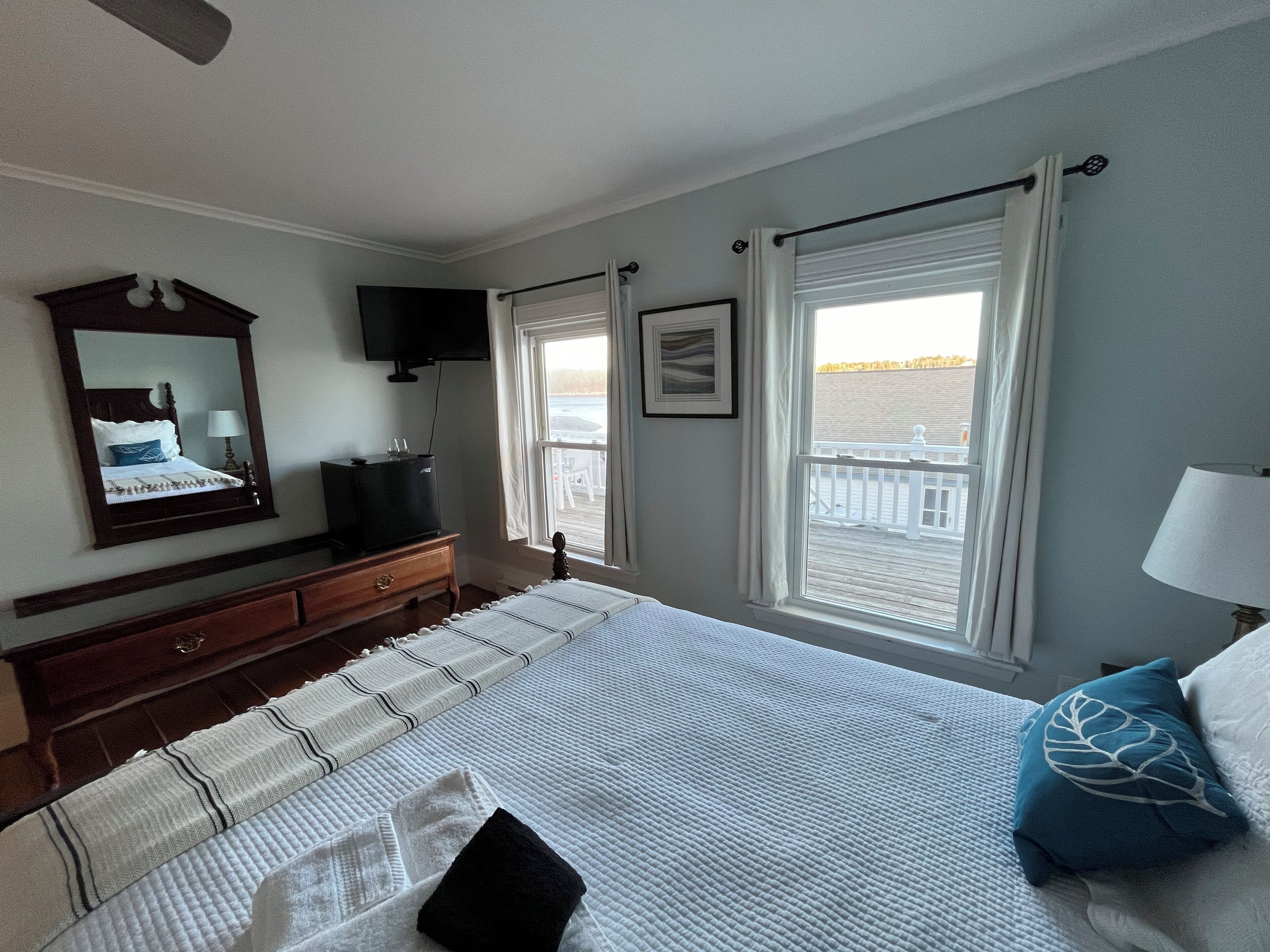 Ein Schlafzimmer mit Bett, Kommode, Fernseher und Fenster mit Blick.
