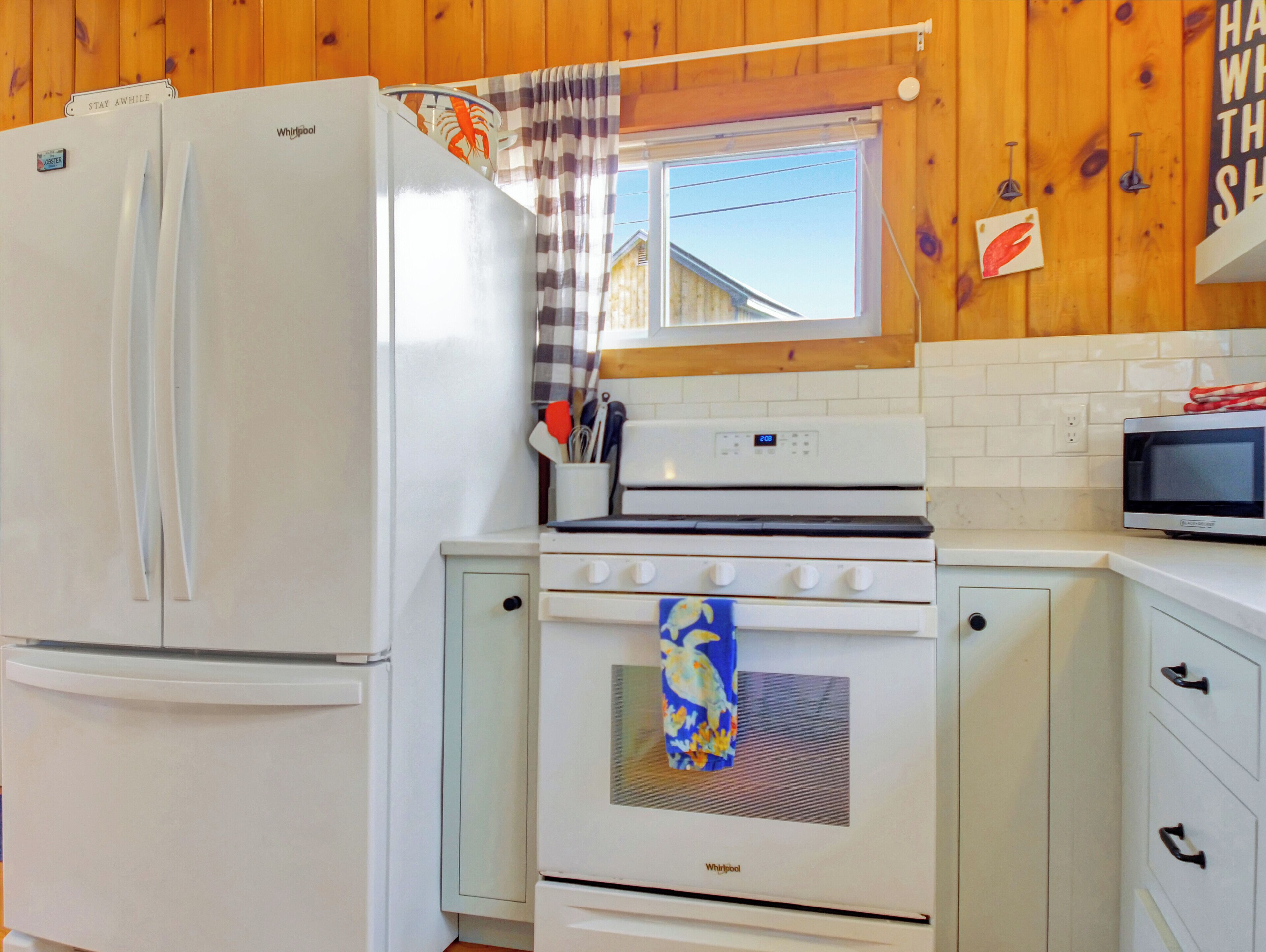 A kitchen with a Whirlpool refrigerator, stove, and microwave.