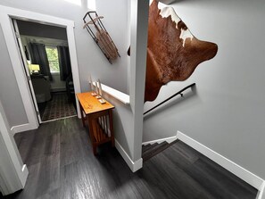 A hallway with a wooden table, a coat rack, and a mounted cow hide on the wall.