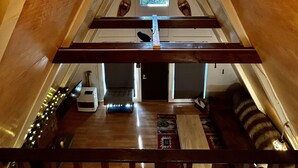 A triangular attic room with wooden beams, a skylight, and a wooden floor.