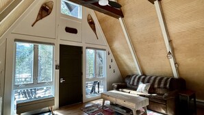 Une chambre confortable située sous les toits, avec un plafond en pente, des poutres apparentes, un canapé, une petite table et un banc.