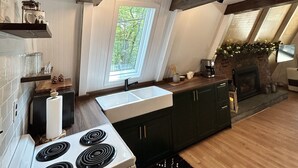 Une cuisine avec un four blanc, des placards noirs et une fenêtre donnant sur des arbres.