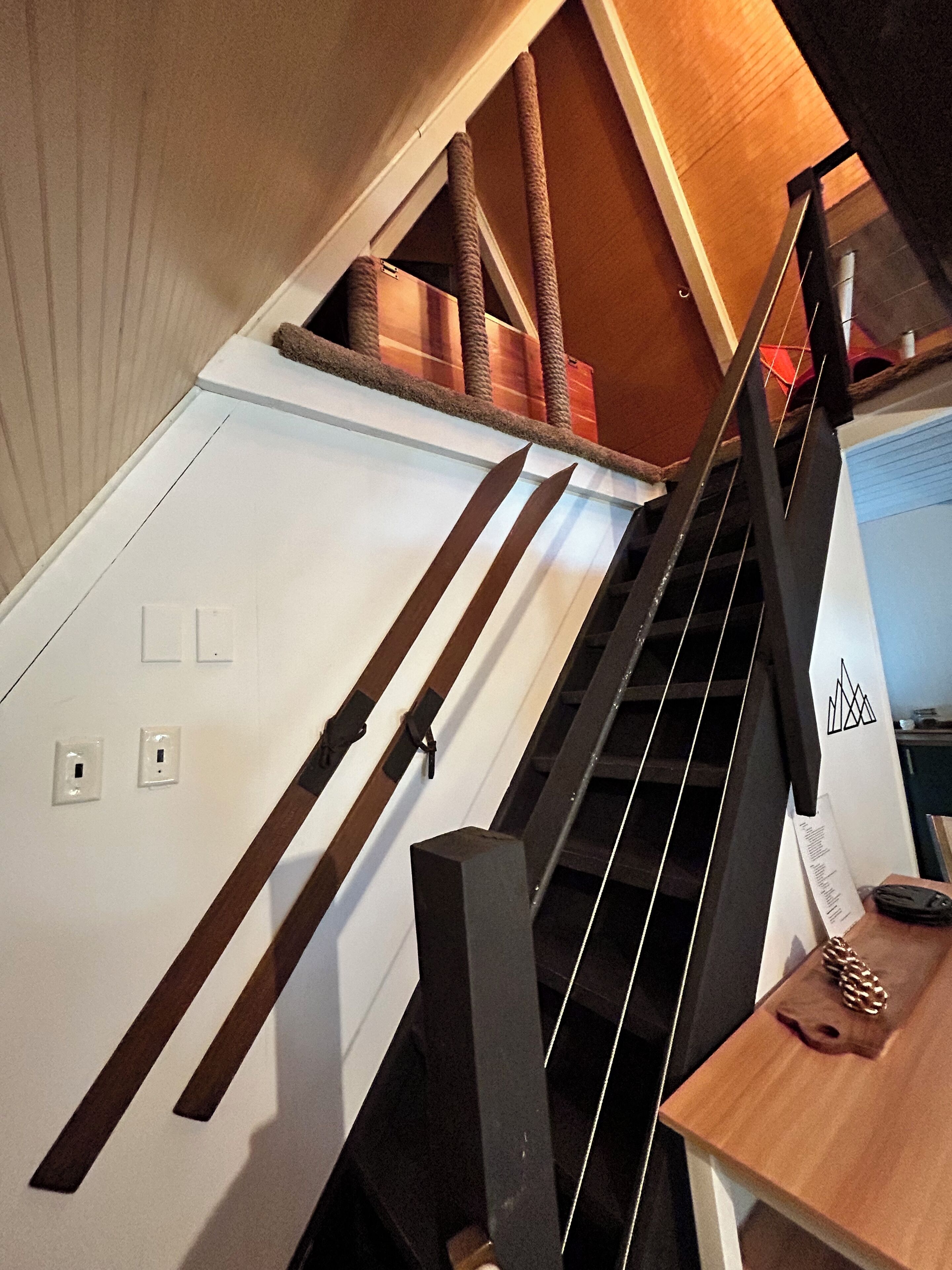 A staircase with a wooden handrail and a cat tree on the landing.