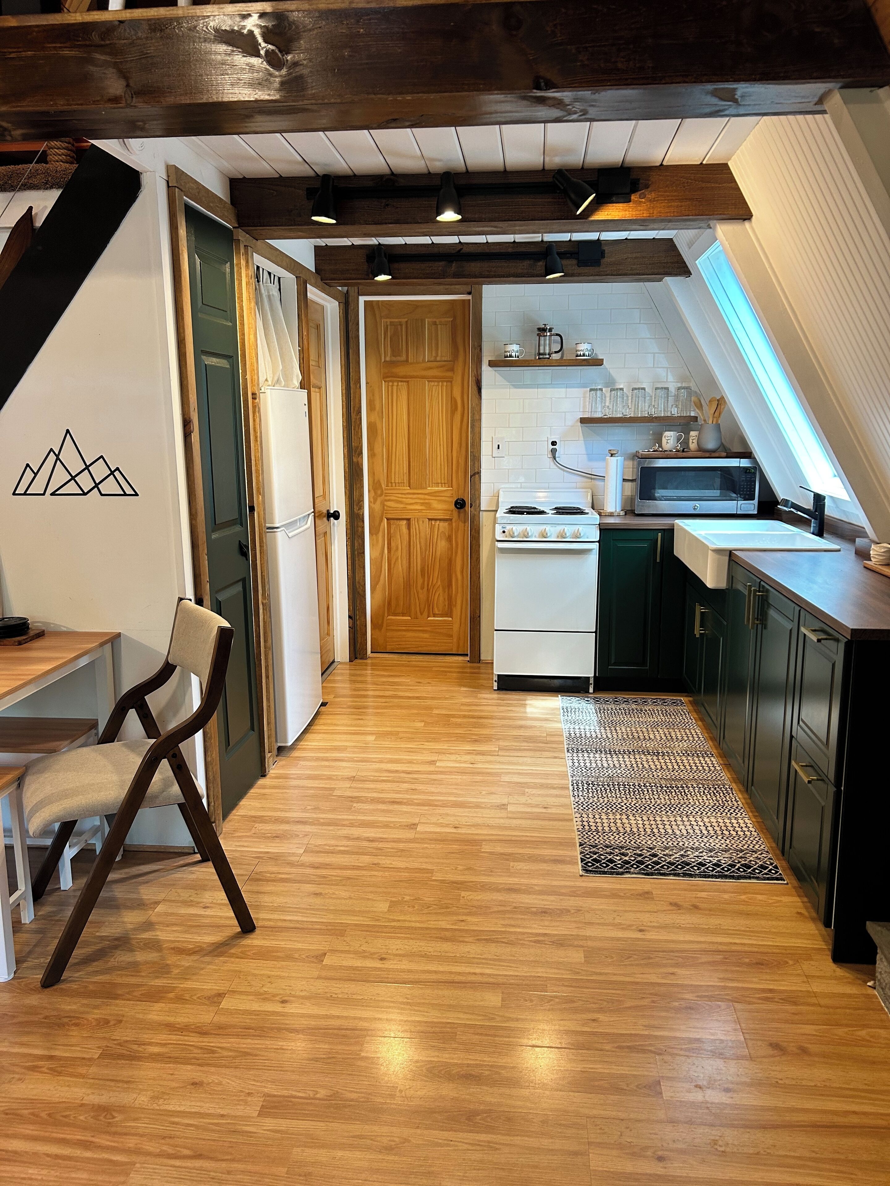 A modern kitchen with wooden flooring, a white stove, and dark cabinets.
