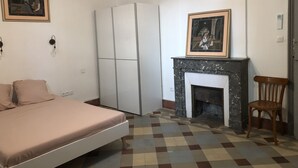 Un dormitorio con cama, armario, chimenea y una silla.