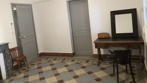 Una habitación con piso a cuadros, un escritorio con espejo, dos puertas y una silla.