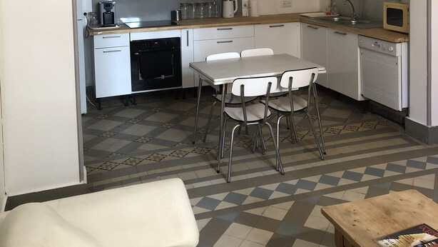 Una cocina compacta con comedor, que incluye un microondas, una cafetera y un lavamanos.