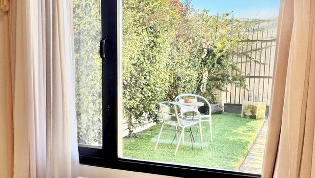 Una habitación con un ventanal grande, una mesa blanca y una alfombra blanca.