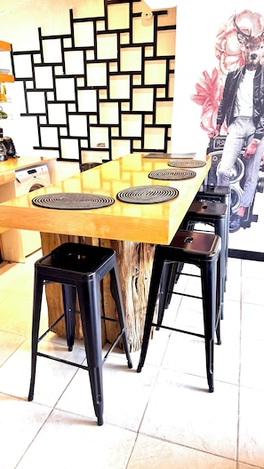 A dining area with a wooden table, black stools, and a wall with a geometric pattern. - Ñireco House—discover Bariloche from here. (San Carlos de Bariloche)