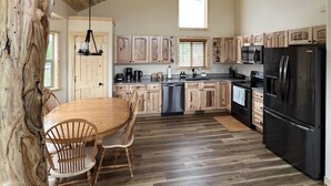 A spacious kitchen with wooden cabinetry, a central island, and a large refrigerator. - Brand New 4-bedroom cabin/stunning views/king bed, Hot Tub!!! (Jefferson)