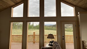 A room with large windows, a wooden ceiling, and a view of a deck with a railing and a lamp. - Brand New 4-bedroom cabin/stunning views/king bed, Hot Tub!!! (Jefferson)