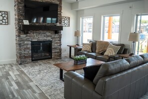 Cozy up by the fireplace in this inviting living room, featuring a comfortable leather sofa and flat-screen TV.